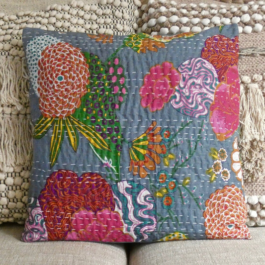 A hand stitched Kantha cushion cover with a printed floral design, displayed on a sofa cushion.