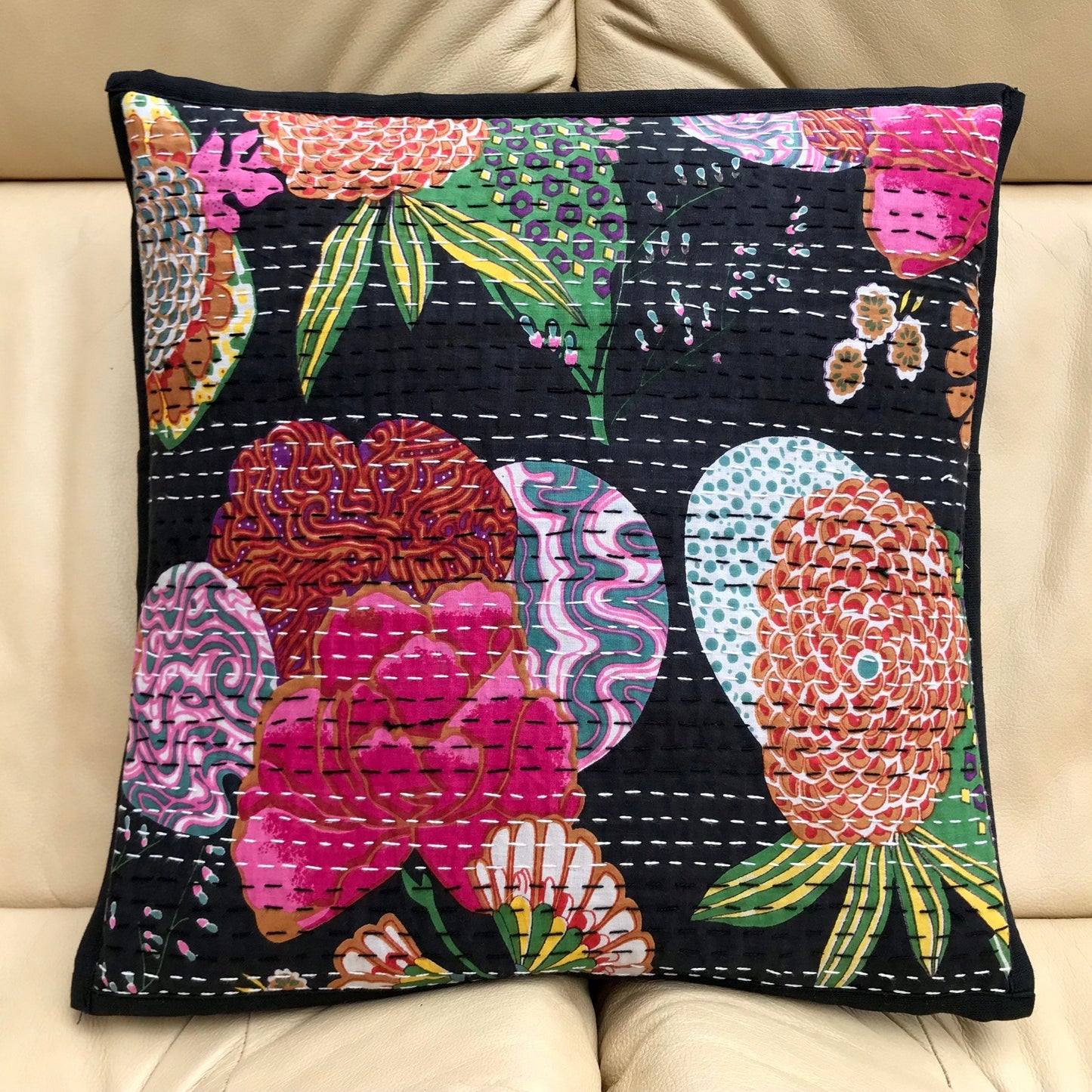A black cushion cover with a colorful floral hand-stitched Kantha design.