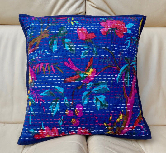 A colorful floral cushion cover with traditional Kantha design, displayed on a sofa.